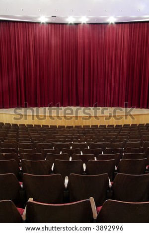 cinema, theater interior; closed red velvet curtain, wooden seats