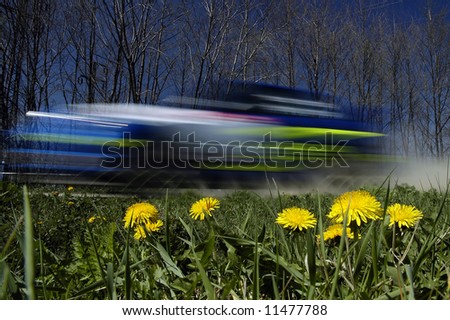 speeding rally car, motion blur, yellow flowers in foreground