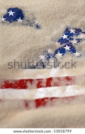 vertical photo of an american flag buried in sand