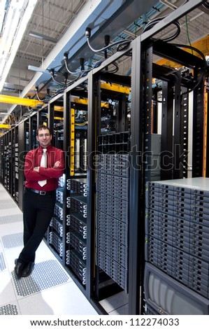 A confident datacenter manager looking at his datacenter equipment with a smile