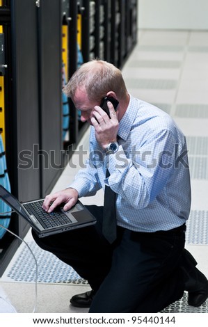 Network administrator is setting up network switches, firewalls and routers using a laptop.