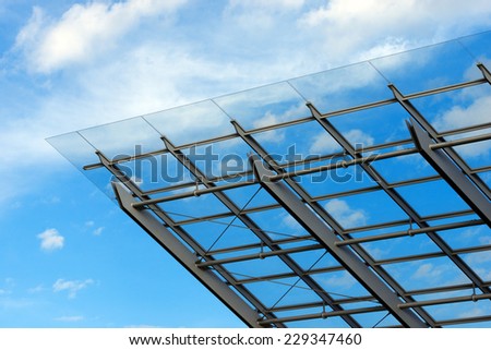 Architectural Details of a Glass and Steel Building / Detail of steel and glass roof of a modern building with blue sky and clouds