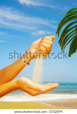 view of  woman’s hand playing with sand on the beach