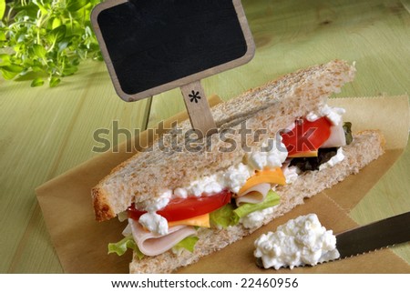 Closeup of a fresh deli sandwich with cottage cheese, luncheon and vegetables and a signboard