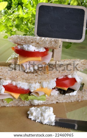 Closeup of a fresh deli double sandwich with cottage cheese, luncheon and vegetables and a signboard