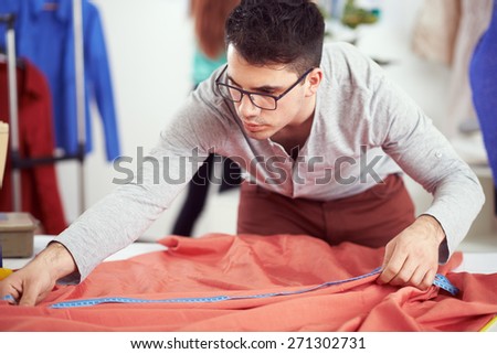 Young designer measuring textile material