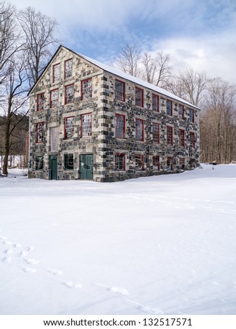 Large Shaker old stone mill building in winter New Hampshire