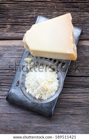 Parmigiano-Reggiano called Parmesan in English after the French name for it, is a hard, granular cheese that is cooked but not pressed. Closeup over rustic wood on metal grate
