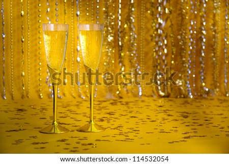 Two flutes of bubbling champagne are against a sparkly background.