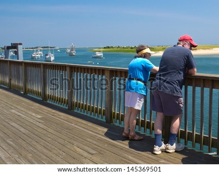 A man and a woman look for seals off the Chatham Fish Pier, MA, on Cape Cod.