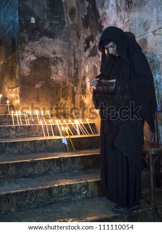 JERUSALEM - AUGUST 25: Unidentified nun prays in the Tomb of Mary in Gethsemane during the feast of the Assumption of the Virgin Mary on August 25, 2012 in old Jerusalem, Israel
