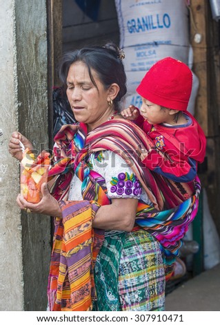 CHICHICASTENANGO , GUATEMALA - JULY 26 : Guatemalan mother with here child buys fruits at the Chichicastenango Market on July 26 2015. This native market is the most colorful in Central America