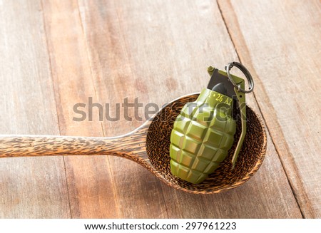 Hand grenade M26A2 model in spoon on wood background