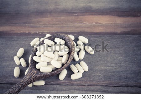 Pills on spoon on wood background cross process vintage style
