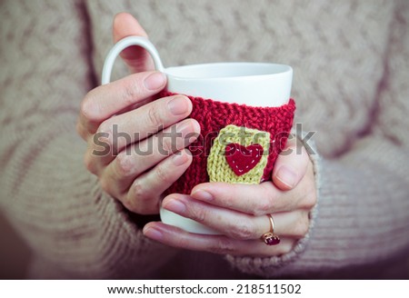 Knitted woolen cups in female hands