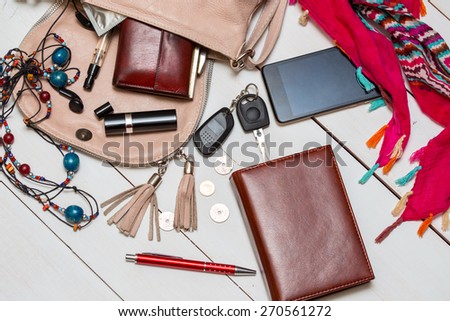 the contents of the female handbag - wallet, keys, phone, lipstick, perfume
