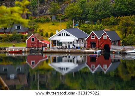 traditional norwegian wooden house to stand at the lakeside and mountains in the distance, norway