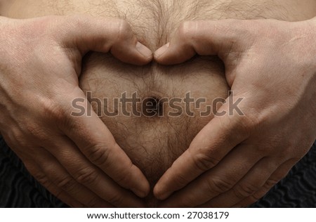 fun pregnancy concept. Man holding a hands like heart shape on his big hairy stomach