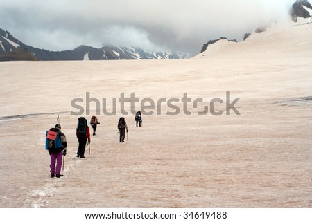 group of hikers sealed by the rope walking by the snow covered ice-rink