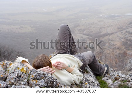 relaxing girl hiker lying on a rocky cliff and looking at the autumn mountain landscape