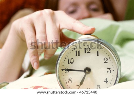 alarm clock disturbing a sleeping woman that is defocused