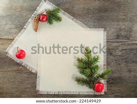 Blank fabric with space for text decorated with branch of christmas tree and red apples at wooden background