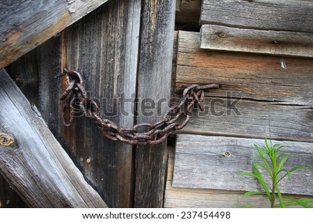 Old rotten wooden door with metal chain