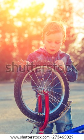 Little boy turning the wheel of his bike on the background of the setting sun. natural composition