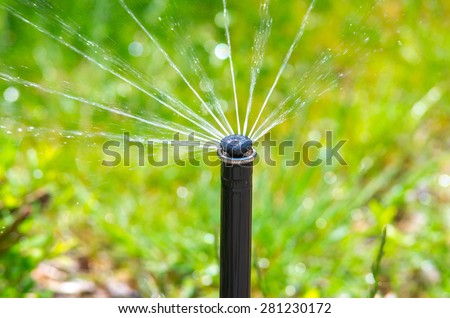 Irrigation equipment watering green grass. Horizontal composition