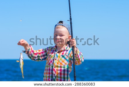 Little boy with mysterious sight holding a fishing pole with his first catch - \