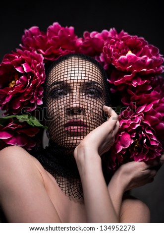 Beautiful brunette wearing dark makeup with flowers and net covering her head