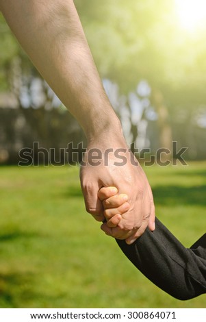 Closeup of a father and son holding hands in a park