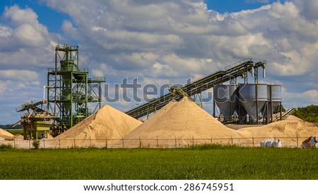Construction sand mining terminal with conveyer belts and silos on a clouded summer day