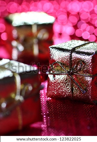 Close up of gifts wrapped up in golden paper on pink background with bokeh