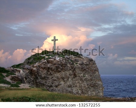 colorful coastal sundown scenery on a caribbean island named Guadeloupe including a summit cross on mountain top