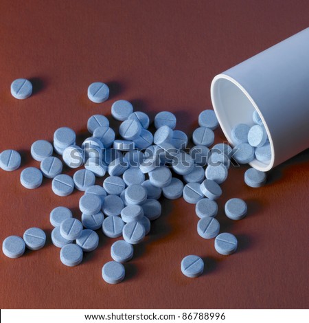 studio shot of blue pills fallen out of the box in red-brown ground