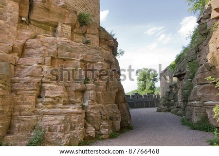 scenery around Wertheim Castle in Southern Germany showing a passage surrounded by rock formations and walls at summer time