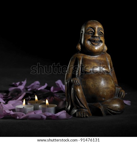 brown Buddha sculpture in dark back with petals and candles
