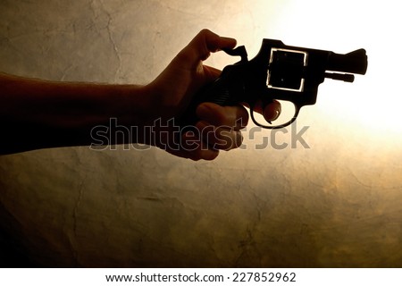 Silhouette of a mans hand with a handgun in brown