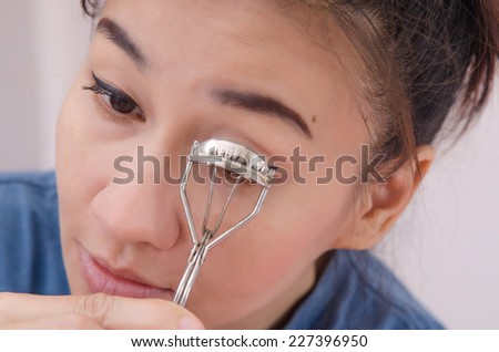 Beauty portrait of young asia woman using eyelash curler