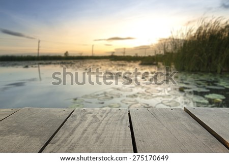 Defocus and blur image of terrace wood and Beautiful lake inside home in sunset time background usage