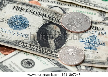 US dollar from 1923 next to half dollar coins. Dollar background. US currency evolving over time, large one USD banknote on top of new dollar bills