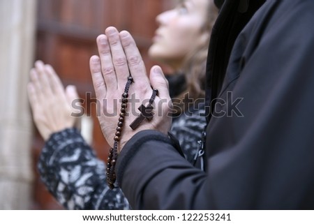 Couple facing the church door, praying with rosary in hand