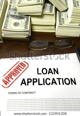 Approved loan application and dollar bills on desk