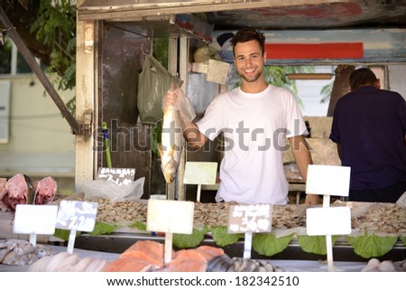 Fishmonger holding a fish at an open retail fish markets.
