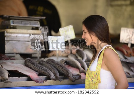 Happy beautiful woman buying fish at a fish shop street market.