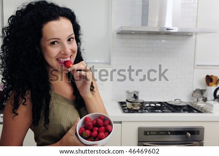 Woman eating strawberries in a modern kitchen