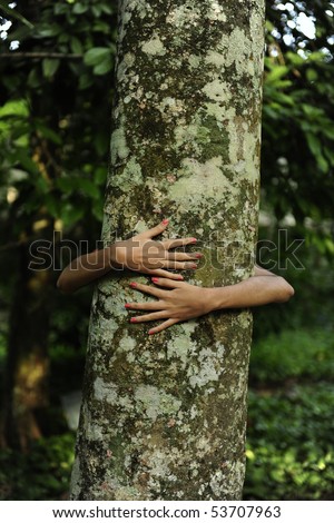 In love with nature: happy woman hugging a tree in the forest