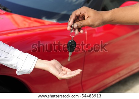 car dealership: woman receiving car key from salesman