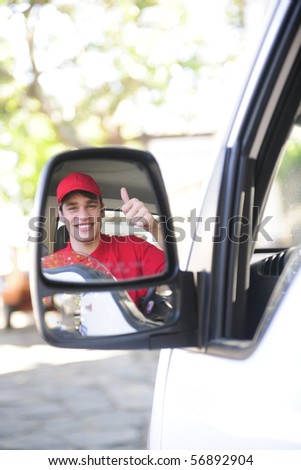 happy postal delivery courier in a van, rear view mirror perspective